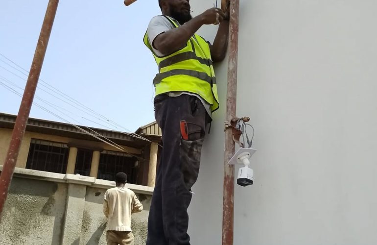 Electrician on scaffold installing wiring and security camera