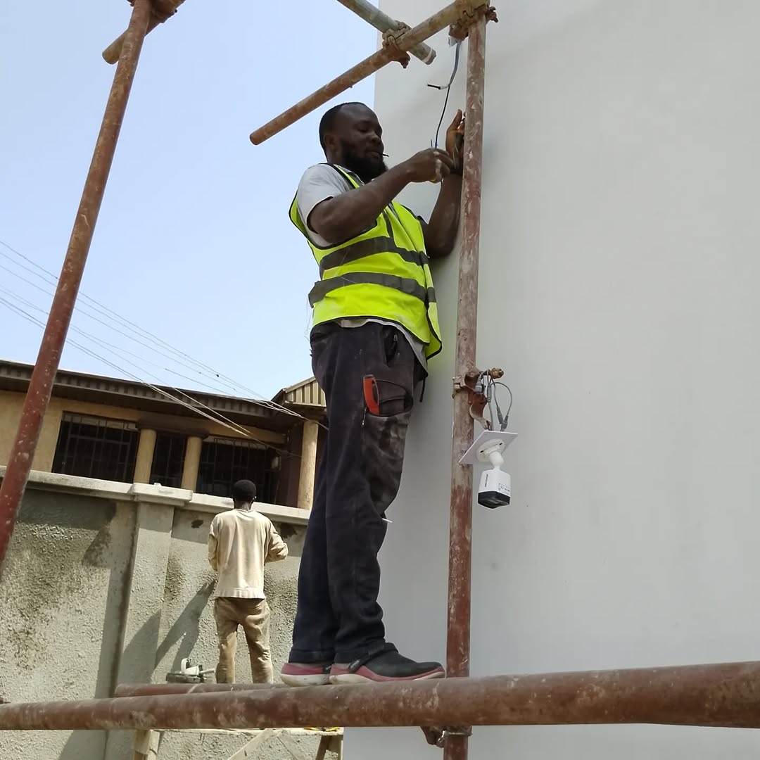 Electrician on scaffold installing wiring and security camera